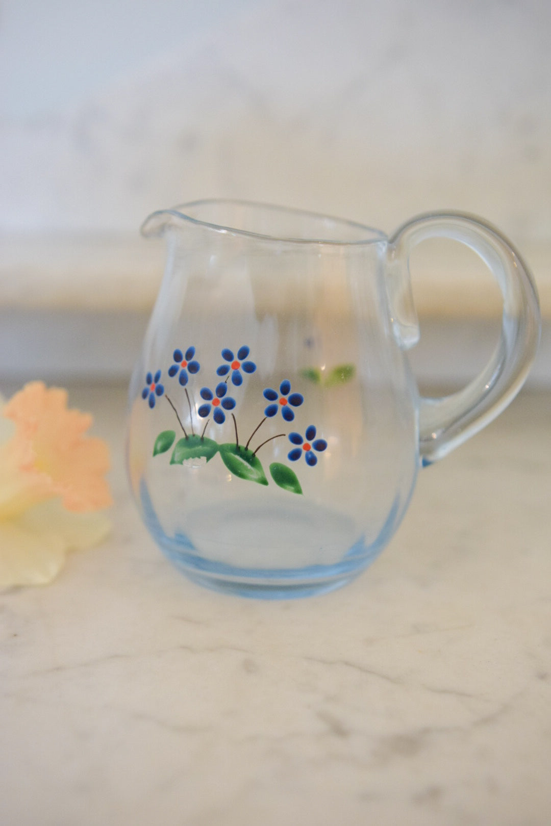 Liten blå kanna i glas med blomstermotiv